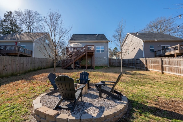 back of house featuring a wooden deck, an outdoor fire pit, and a yard