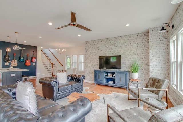 living room featuring sink, ceiling fan with notable chandelier, and light wood-type flooring