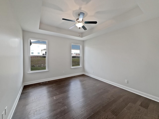 unfurnished room with ceiling fan, dark hardwood / wood-style floors, and a raised ceiling