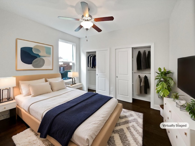 bedroom featuring ceiling fan, dark wood-type flooring, and multiple closets