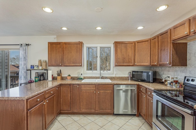 kitchen with sink, light tile patterned floors, kitchen peninsula, stainless steel appliances, and a textured ceiling