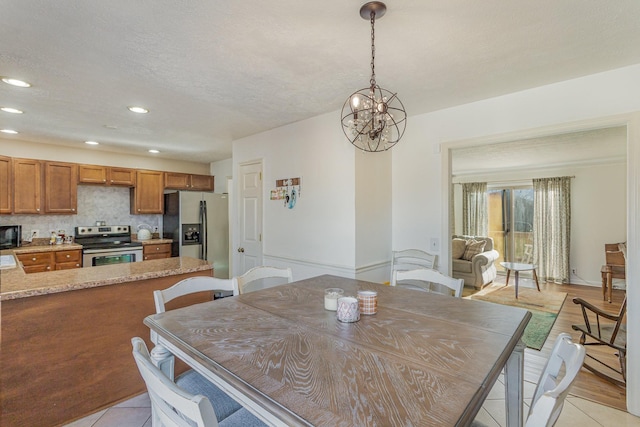 tiled dining area featuring an inviting chandelier and a textured ceiling