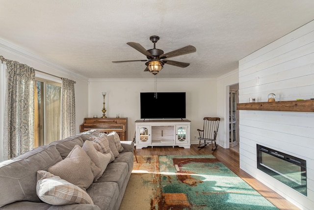 living room featuring crown molding, hardwood / wood-style flooring, ceiling fan, a fireplace, and a textured ceiling