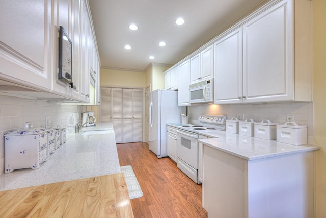 kitchen with light stone counters, white appliances, light hardwood / wood-style flooring, and white cabinets