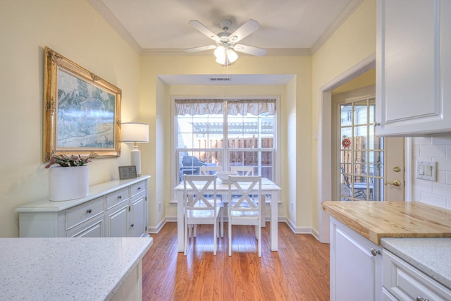 dining room with ornamental molding, ceiling fan, and light hardwood / wood-style floors