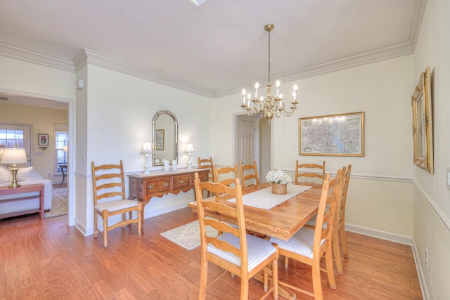 dining space with an inviting chandelier, ornamental molding, and light hardwood / wood-style floors