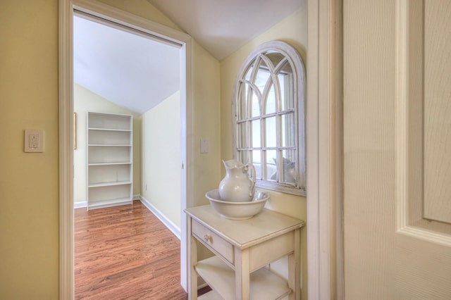 hall featuring hardwood / wood-style flooring and vaulted ceiling