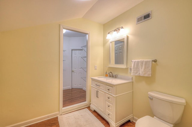 bathroom featuring vanity, toilet, vaulted ceiling, and wood-type flooring