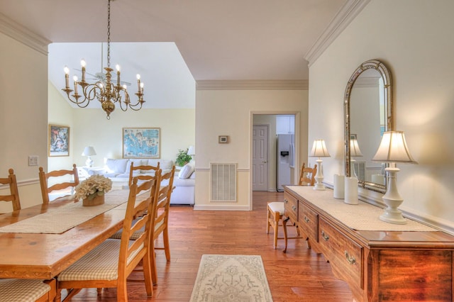 dining space featuring wood-type flooring, ornamental molding, and a notable chandelier