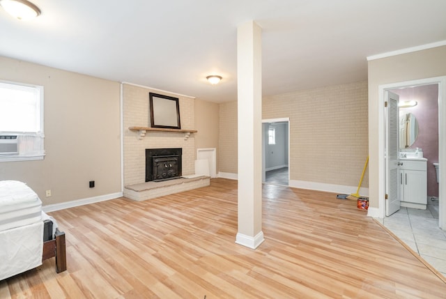 interior space with a brick fireplace, light hardwood / wood-style flooring, and brick wall