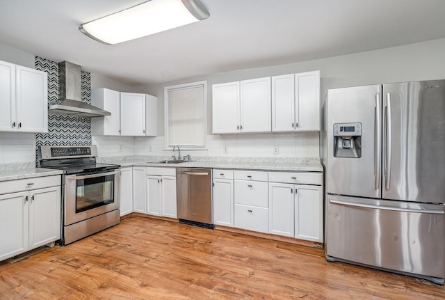 kitchen featuring sink, white cabinets, stainless steel appliances, wall chimney range hood, and light hardwood / wood-style flooring