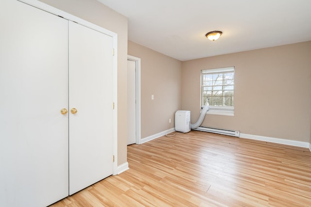 unfurnished bedroom featuring light hardwood / wood-style flooring and a baseboard heating unit