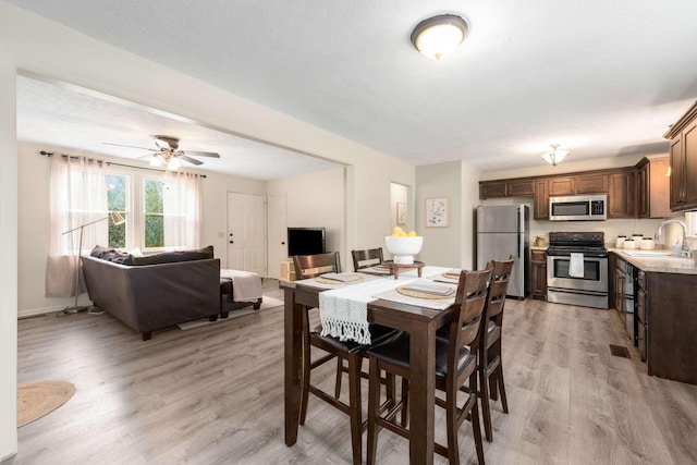 dining space featuring ceiling fan, sink, and light hardwood / wood-style flooring