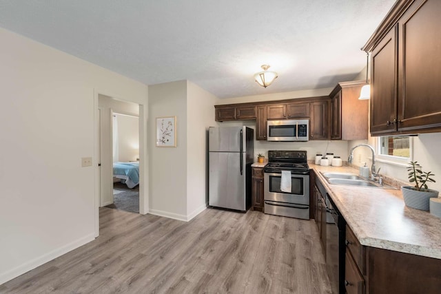 kitchen with sink, light hardwood / wood-style floors, stainless steel appliances, dark brown cabinets, and a textured ceiling