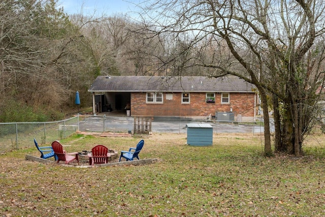 rear view of house with a patio area, a yard, central AC unit, and a fire pit