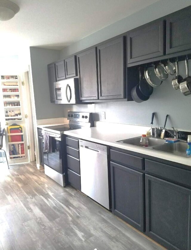 kitchen with appliances with stainless steel finishes, sink, and light wood-type flooring