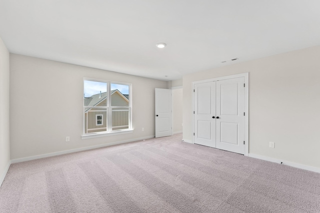 unfurnished bedroom with light colored carpet and a closet