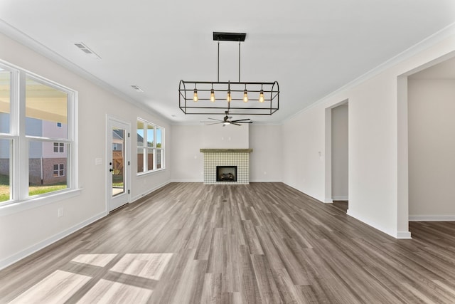 unfurnished living room featuring wood-type flooring, ornamental molding, a tile fireplace, and ceiling fan