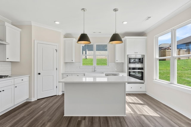 kitchen with stainless steel appliances, white cabinetry, hanging light fixtures, and a center island