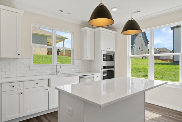 kitchen featuring pendant lighting, sink, appliances with stainless steel finishes, light stone countertops, and white cabinets