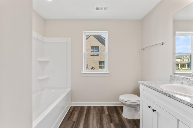 full bathroom featuring vanity, hardwood / wood-style floors, toilet, and washtub / shower combination