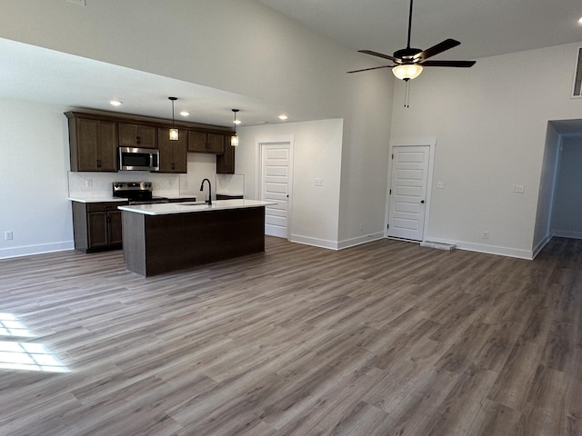 kitchen with sink, hanging light fixtures, a center island with sink, appliances with stainless steel finishes, and hardwood / wood-style floors