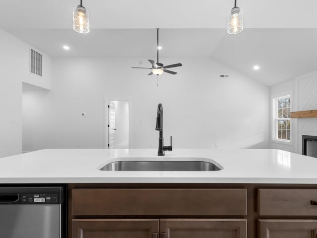 kitchen with lofted ceiling, dark brown cabinetry, sink, decorative light fixtures, and stainless steel dishwasher