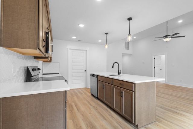 kitchen featuring sink, a kitchen island with sink, stainless steel appliances, light hardwood / wood-style floors, and decorative light fixtures