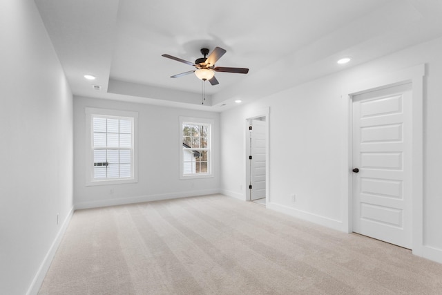 carpeted empty room featuring a raised ceiling and ceiling fan