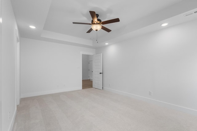 carpeted empty room featuring ceiling fan and a tray ceiling