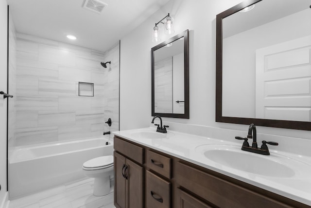 full bathroom with tiled shower / bath, vanity, and toilet