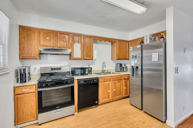 kitchen with light hardwood / wood-style floors, sink, a textured ceiling, and black appliances