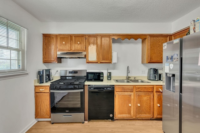 kitchen with light wood-type flooring, sink, a textured ceiling, and black appliances