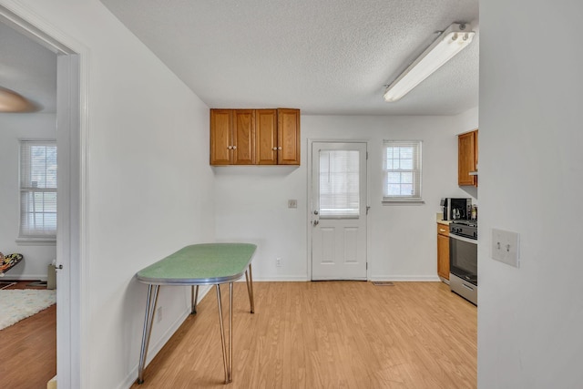 kitchen featuring stainless steel range, a wealth of natural light, light hardwood / wood-style floors, and a textured ceiling