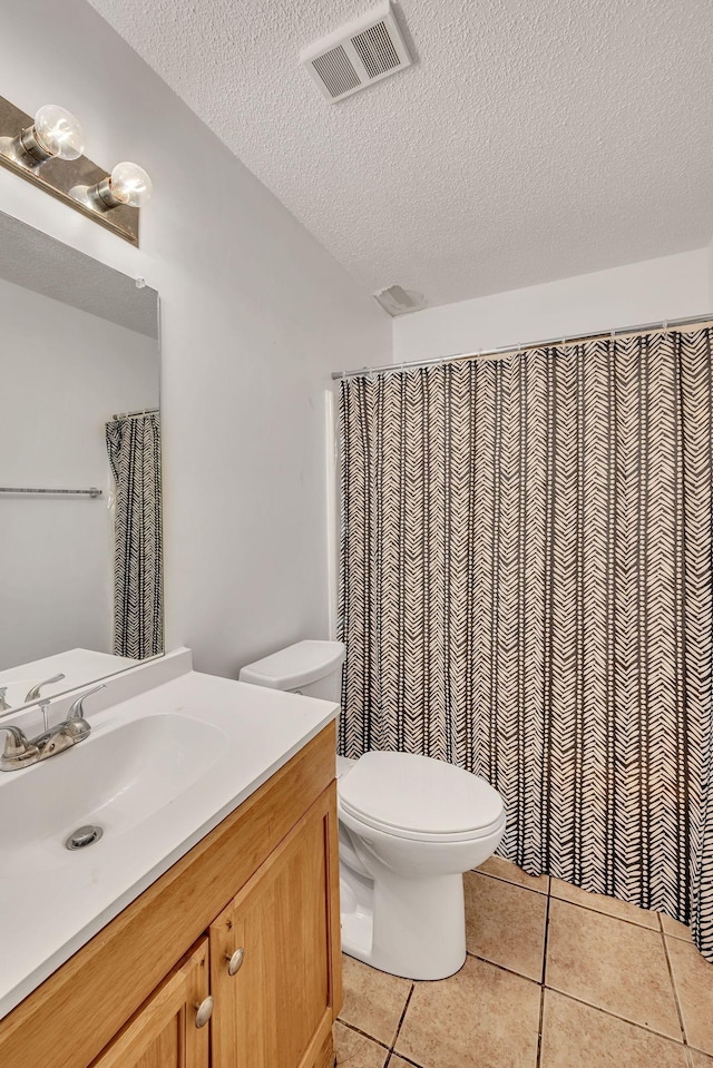 bathroom with vanity, toilet, tile patterned flooring, and a textured ceiling