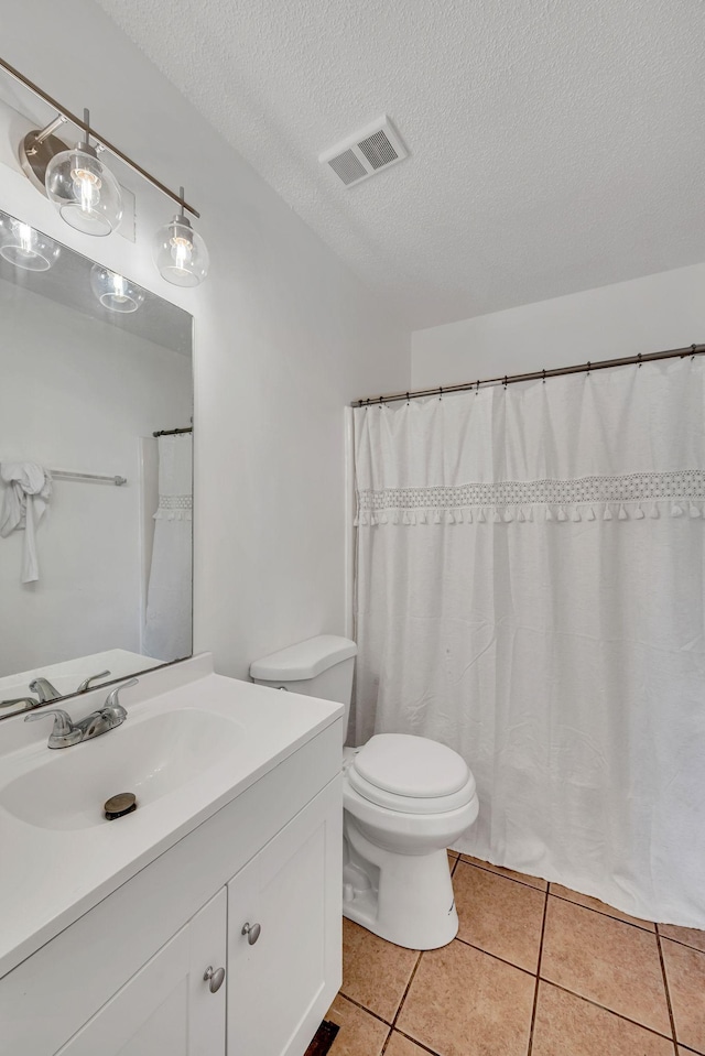 bathroom with tile patterned flooring, vanity, a textured ceiling, and toilet