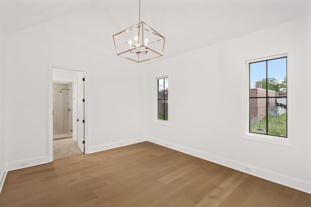 spare room with hardwood / wood-style flooring, lofted ceiling, and a chandelier