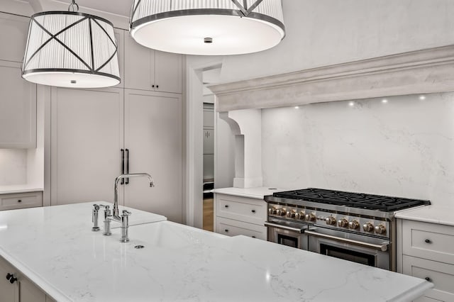 kitchen featuring sink, light stone counters, a kitchen island, range with two ovens, and backsplash