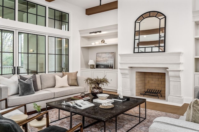 living room with hardwood / wood-style flooring, a towering ceiling, and built in shelves