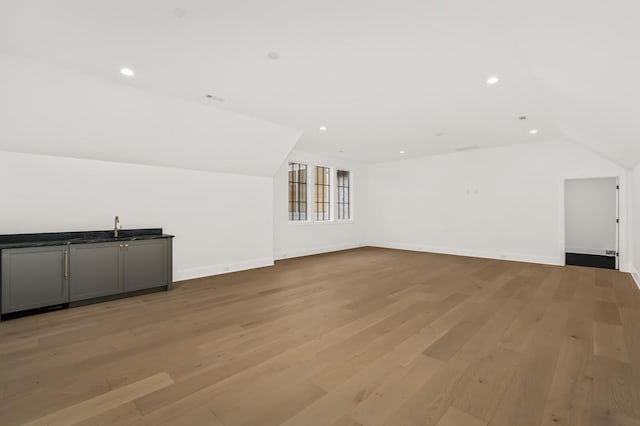 additional living space with vaulted ceiling and light wood-type flooring