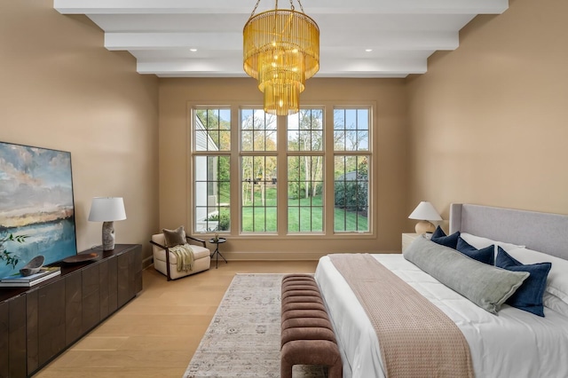 bedroom featuring beamed ceiling, a chandelier, and light wood-type flooring