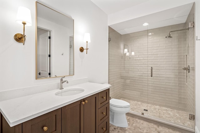 bathroom featuring vanity, a shower with shower door, and toilet