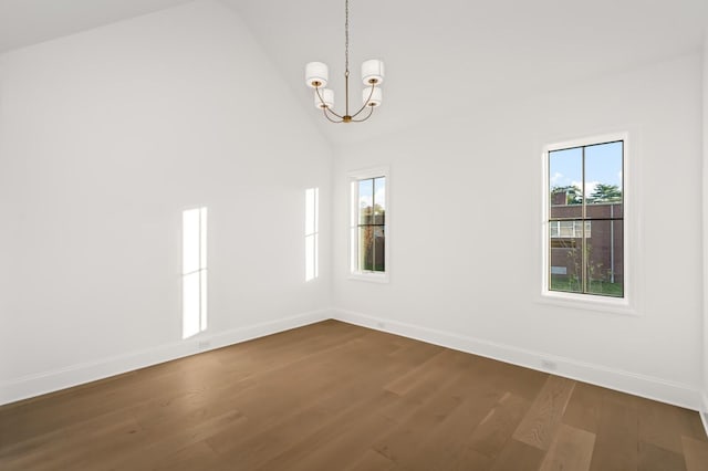 unfurnished room with lofted ceiling, a notable chandelier, dark wood-type flooring, and a healthy amount of sunlight