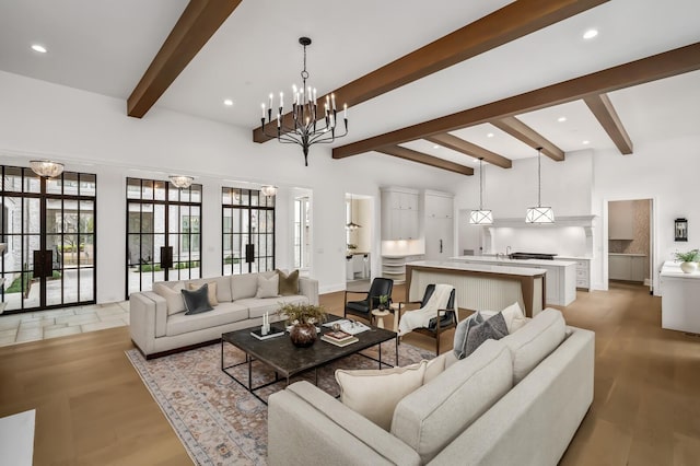 living room with beam ceiling, a notable chandelier, and light wood-type flooring