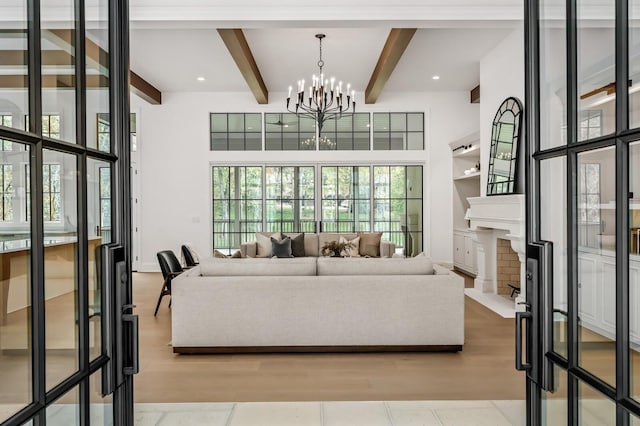 living room featuring beamed ceiling, a towering ceiling, an inviting chandelier, and light hardwood / wood-style floors