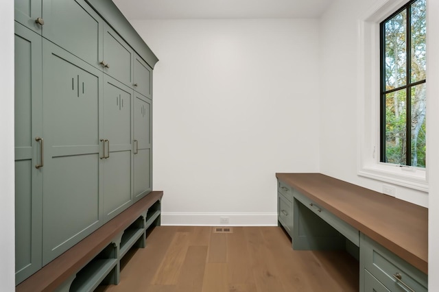 mudroom with hardwood / wood-style flooring and built in desk