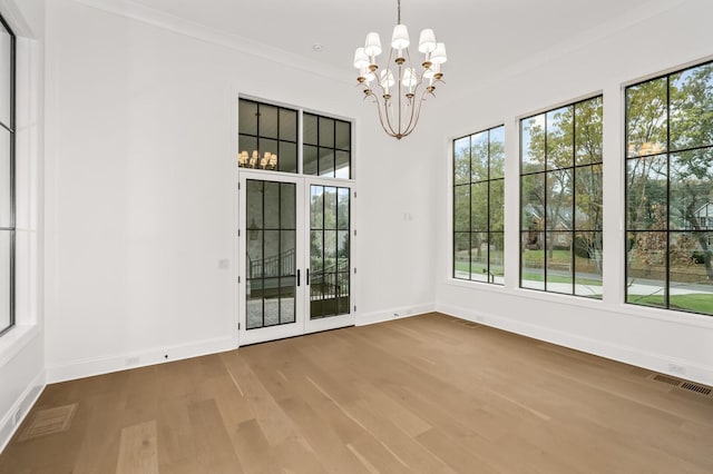 interior space with a notable chandelier, wood-type flooring, and ornamental molding