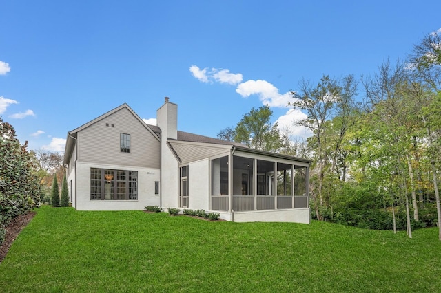 rear view of house with a yard and a sunroom