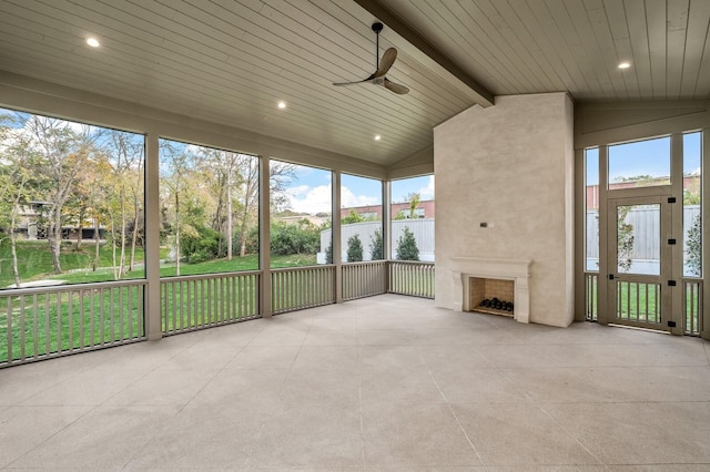 unfurnished sunroom featuring wood ceiling, ceiling fan, a fireplace, and vaulted ceiling with beams