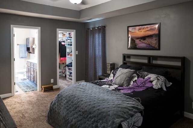 bedroom with ensuite bath, a spacious closet, carpet floors, and a closet